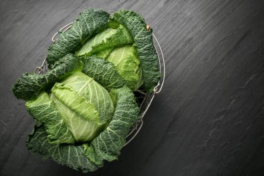 Siyah masada metal sepetin içinde taze Savoy lahanaları. Metin için boşluk