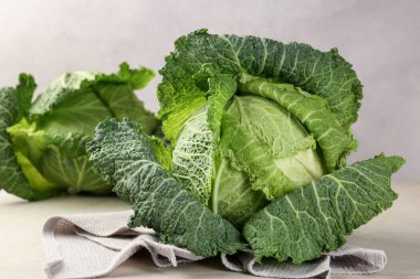 Fresh Savoy cabbages on light grey table, closeup