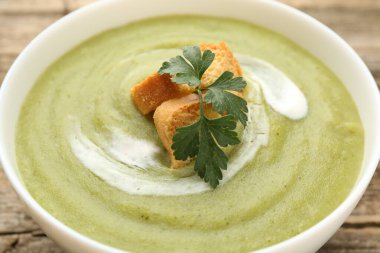 Tasty broccoli cream soup with croutons in bowl on table, closeup