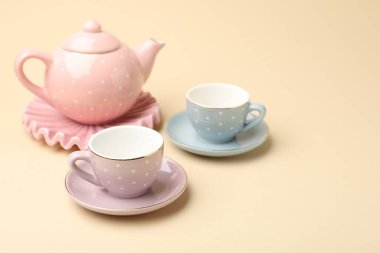 Bej arka plandaki çocuklar için seramik çay seti, yakın plan. Metin için boşluk