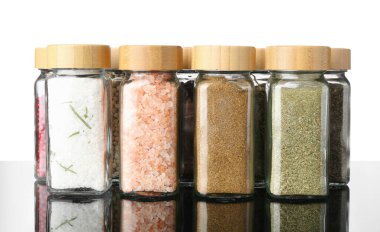 Ayna yüzeyindeki kavanozlardaki farklı baharatlar beyaz arkaplana karşı