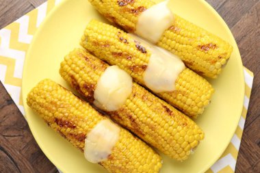 Ahşap masadaki soslu, leziz mısır koçanları.