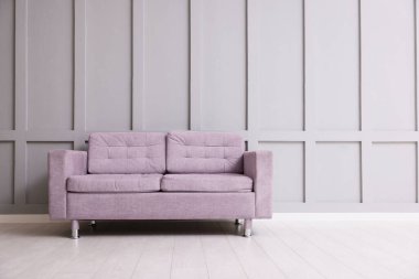 Gri duvarın yanındaki rahat menekşe kanepe