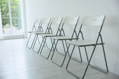 Beyaz duvarın yanında bir sürü şık sandalye.