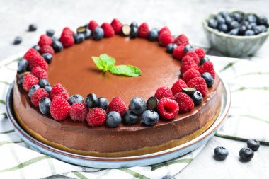 Delicious chocolate cheesecake with berries and mint on grey table, closeup