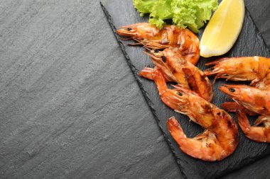 Lezzetli deniz ürünleri yemeği. Siyah masada limonlu ve marullu ızgara karides. Metin için boşluk