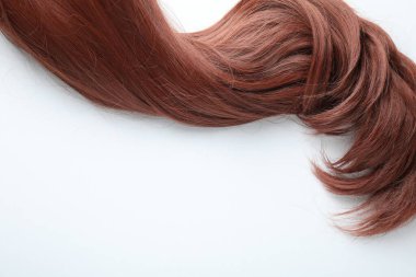 Beyaz arka planda kestane rengi saç teli, üst manzara. Metin için boşluk