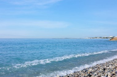 Dalgalı deniz manzarası ve kumsaldaki çakıl taşları.