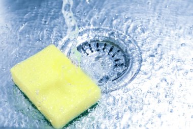 Water going down drain and sponge in sink, closeup