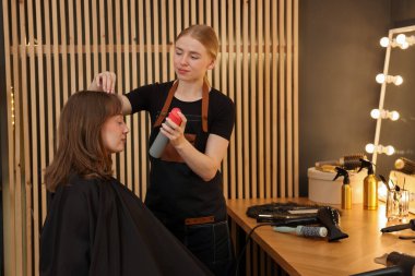 Profesyonel kuaför müşteriyle kuaförde çalışıyor.