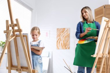 Meslek seçimi. Anne kızına stüdyoda resim yapmayı öğretiyor.