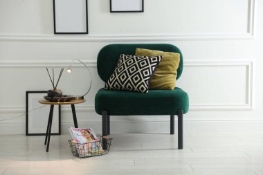 Şık lamba, sazlık dağıtıcı ve yastıklı koltuğun yanında dergi.