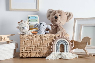 Beyaz duvarın yanındaki ahşap masada farklı oyuncaklar ve dekorlar.