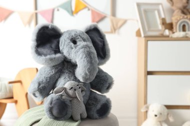 Çocuk odasında puf üzerinde sevimli oyuncak filler, yakın plan. Metin için boşluk