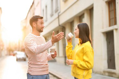 Paket kahve. Şehir caddesinde kağıt bardak içen bir çift.