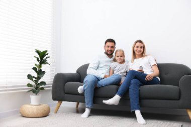 Evdeki kanepede klimalı, uzaktan kumandalı mutlu bir aile.