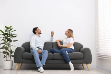 Evdeki koltukta uzaktan kumandayla klima kullanan çift.