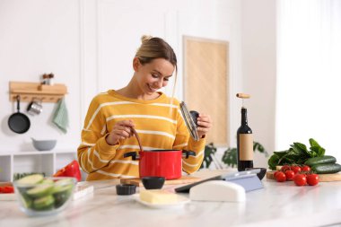 Mutfaktaki masada yemek yapan gülümseyen kadın.