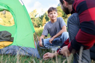 Baba ve oğul kamp çadırı kuruyor, kapatıyorlar.