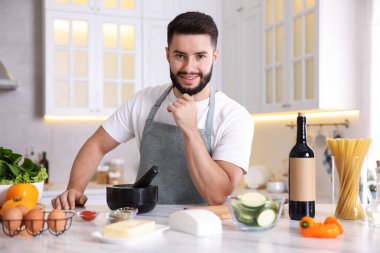 Mutfaktaki masada yemek yapan gülümseyen adamın portresi.