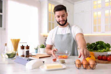 Mutfaktaki masada yemek pişiren gülümseyen adam.