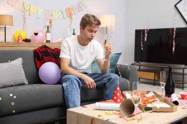 Bir bardak alkollü adam partiden sonra dağınık bir odada kanepede akşamdan kalma.