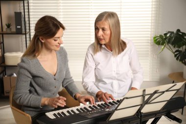 Öğretmenim kadınlara evde piyano çalmayı öğretiyor.