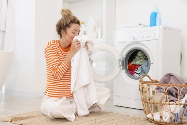Çamaşır makinesinin yanında çamaşır makinesi olan bir kadın.