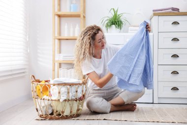 Çamaşır makinesinin yanında çamaşır makinesi olan bir kadın.