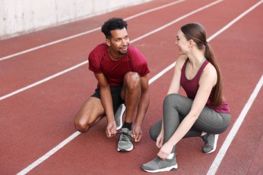 Stadyumda ayakkabı bağcıklarını bağlayan koşucular