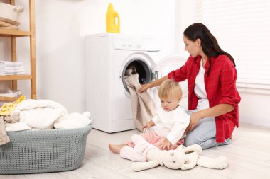 Ev hanımı ve bebeği evde çamaşır yıkıyor.