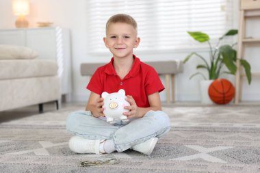 Evde cep harçlığı ve kumbarası olan küçük bir çocuk.