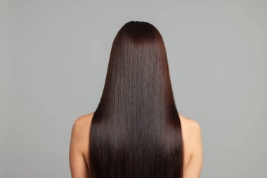 Açık gri arkaplandaki katman prosedüründen sonra güzel pürüzsüz saçlı bir kadın.