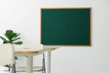Boş yeşil karatahta, masalar, sandalyeler ve bitkiler sınıfta