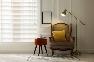 Kitaplarla, koltukla, lambayla ve boş çerçeveyle oturma odasındaki beyaz duvara, mesaj için yere. İç tasarım