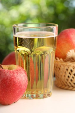 Lezzetli elma şarabı cam ve elmalar beyaz ahşap masa üzerinde, yakın plan