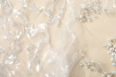 Bej arka planda pulları ve incileri olan güzel dantel kumaş.