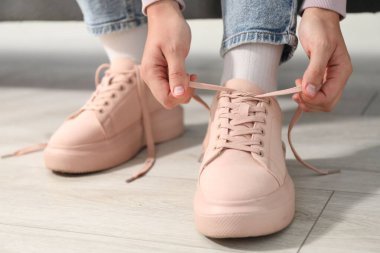 Bej ayakkabı bağcığını içeri bağlayan kadın, yakın plan.