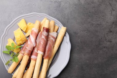 Grissini ekmek çubukları, jambon ve peynirli gri masa, üst manzara. Metin için boşluk