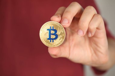 Kripto para birimi. Gri arka planda altın bitcoin 'i olan adam, yakın plan. Metin için boşluk