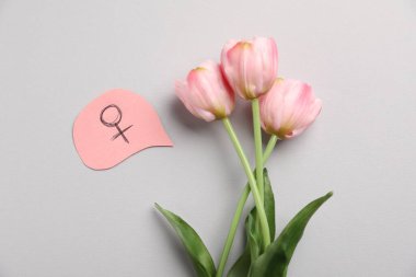 Menopoz. Açık gri arka planda kadın cinsiyet sembolü ve laleler, düz yatıyordu