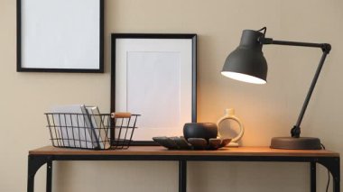 Bej duvarın yanında şık ve dekorlu konsol masası. Kitapları sepete koyan kadın, yakın plan.