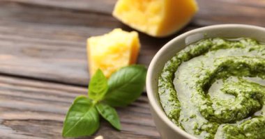 Tabakta taze pesto sosu ve ahşap masada malzemeler, yakın plan. Kamera sağa hareket ediyor