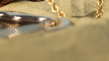 Kum üzerinde güzel altın mücevherlerin şık sunumu, yakın plan.