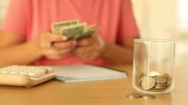 Para dolu cam kavanoz ve tahta masada kadın bütçesi, seçici odaklanma