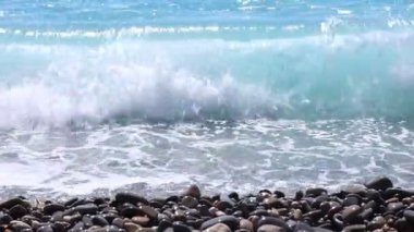Dalgalı deniz manzarası ve kumsaldaki çakıl taşları, yakın çekim.