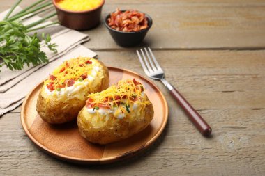 Ekşi kremalı fırında patates, yeşil soğan, peynir ve pastırma ahşap masada servis edilir.