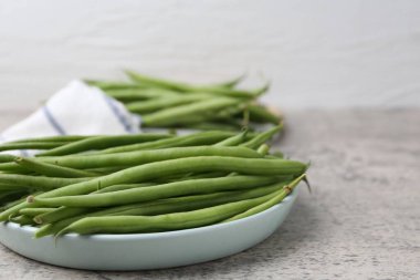 Fresh green bean pods on grey textured table, closeup. Space for text