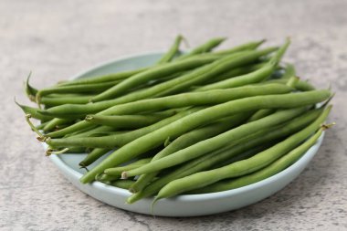 Fresh green bean pods on grey textured table, closeup