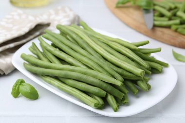 Fresh green bean pods on white tiled table, closeup